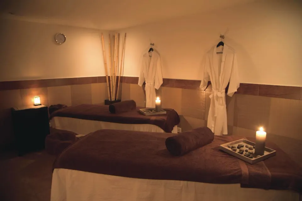 Spa treatment room with massage tables, robes, candles, and bamboo decor at Hotel Riu Palace Aruba.