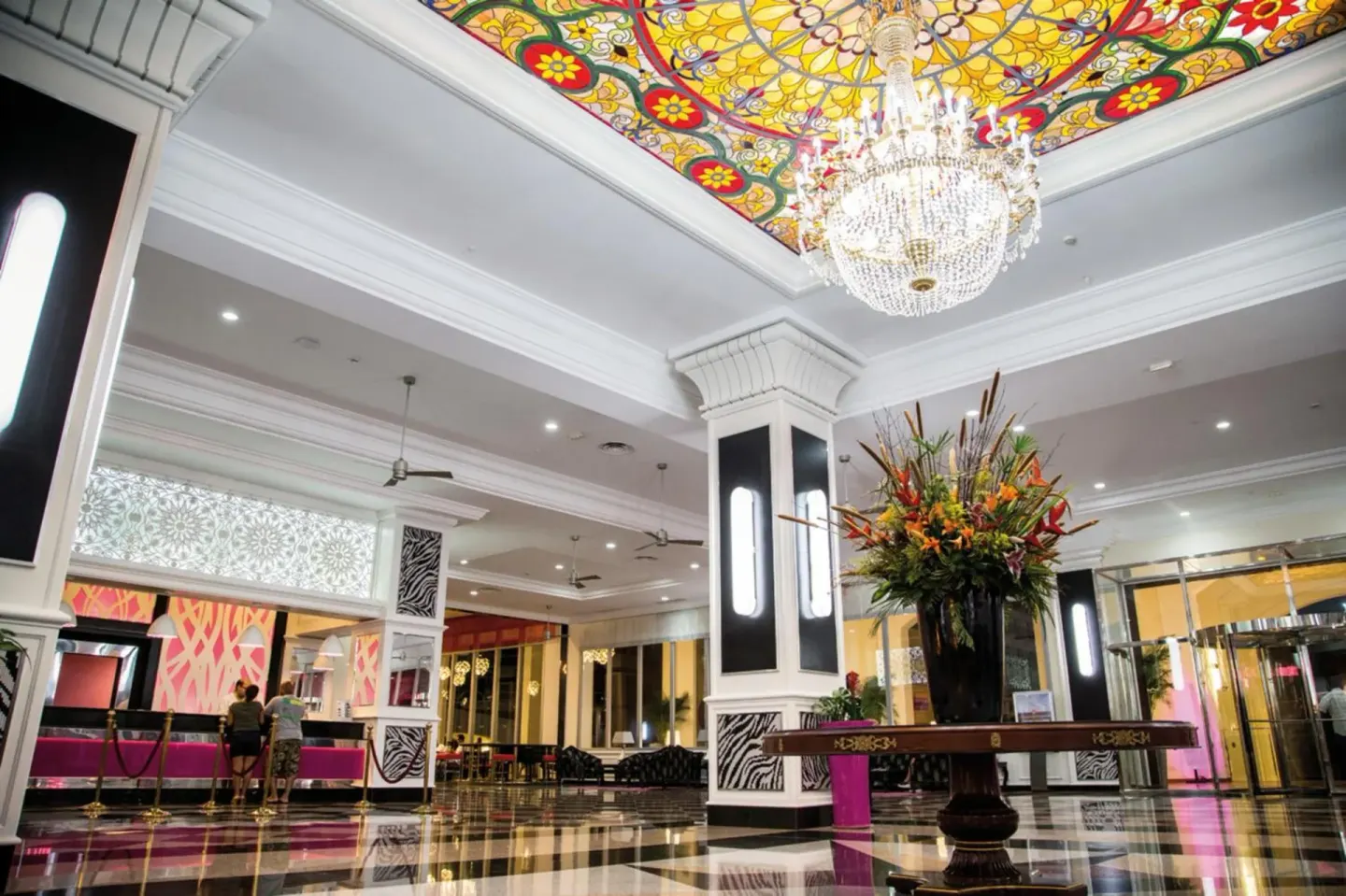 Lobby ceiling with stained glass, chandelier and columns at Hotel Riu Palace Aruba.