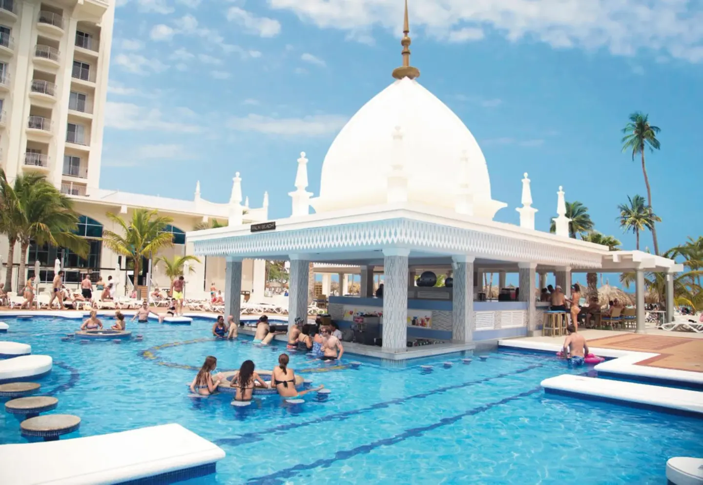 Swim-up pool bar and guests in the water at Hotel Riu Palace Aruba.