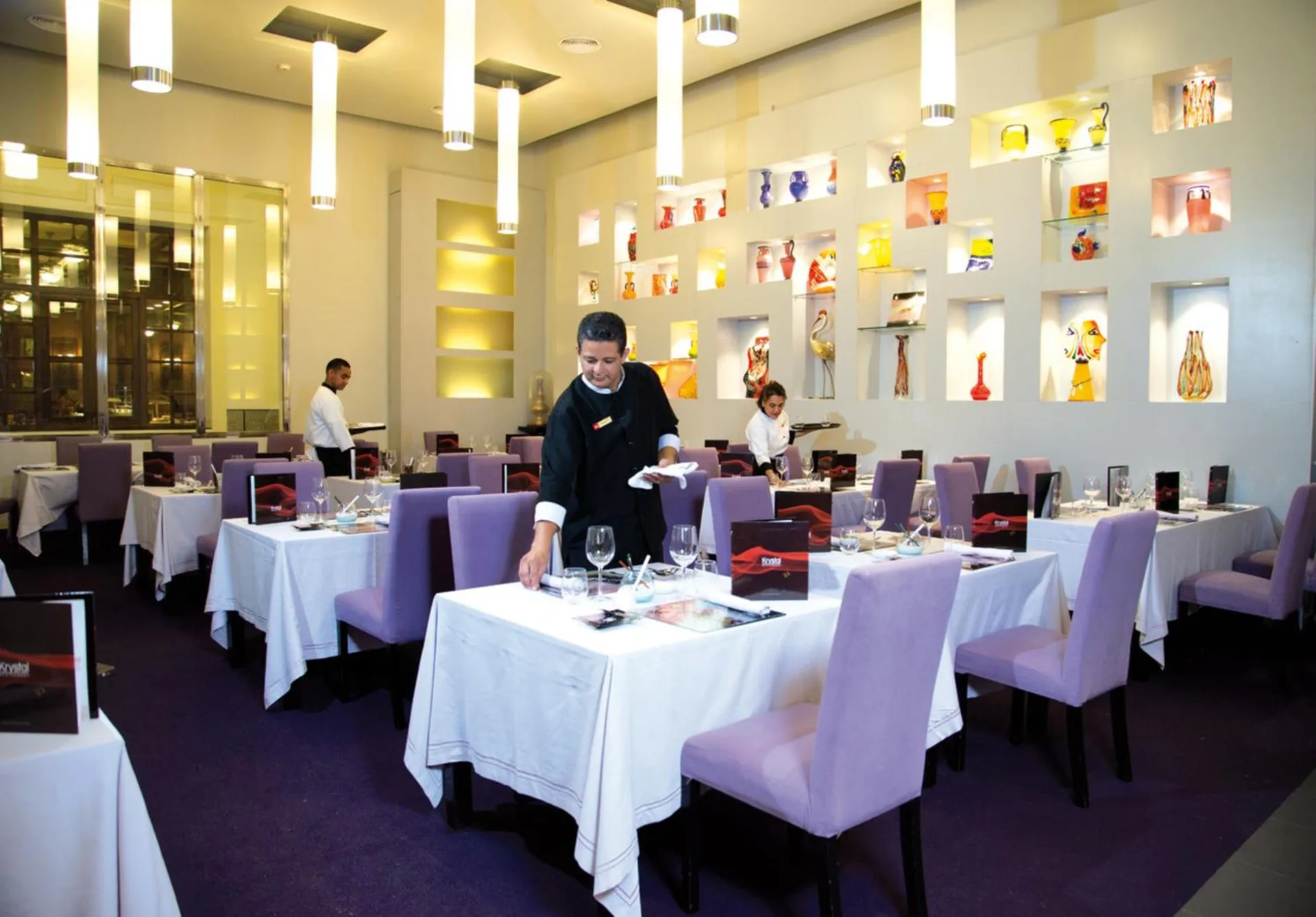 Krystal dining room with set tables and purple chairs at Hotel Riu Palace Aruba.