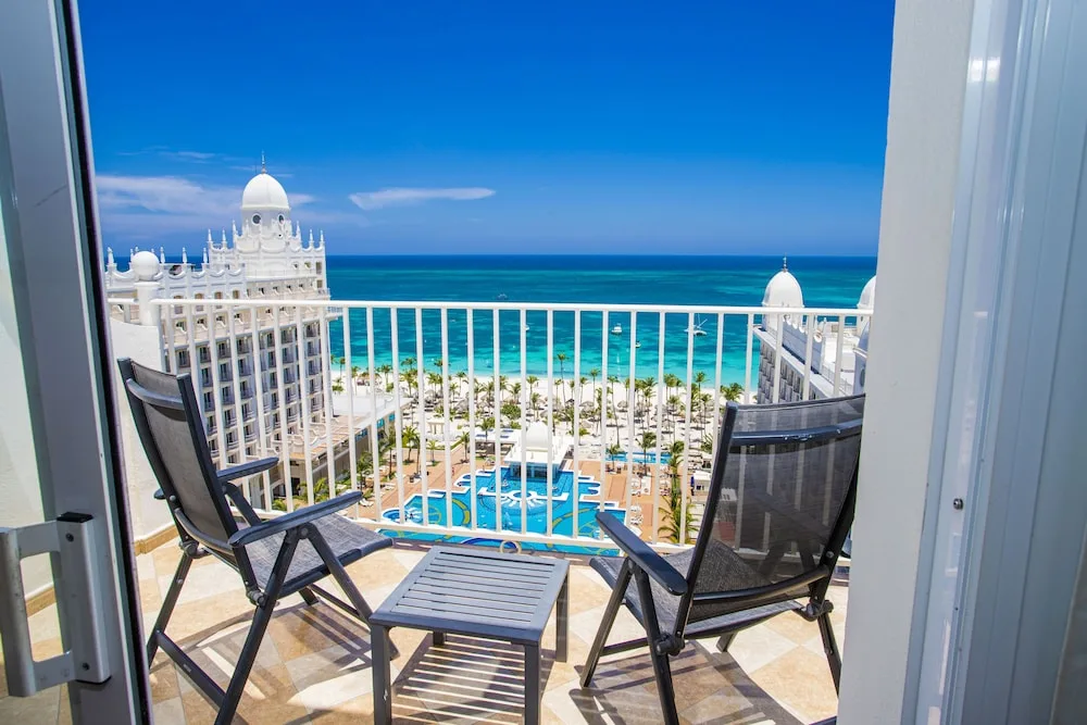 Junior Suite Ocean View balcony with chairs and sea view at Hotel Riu Palace Aruba.