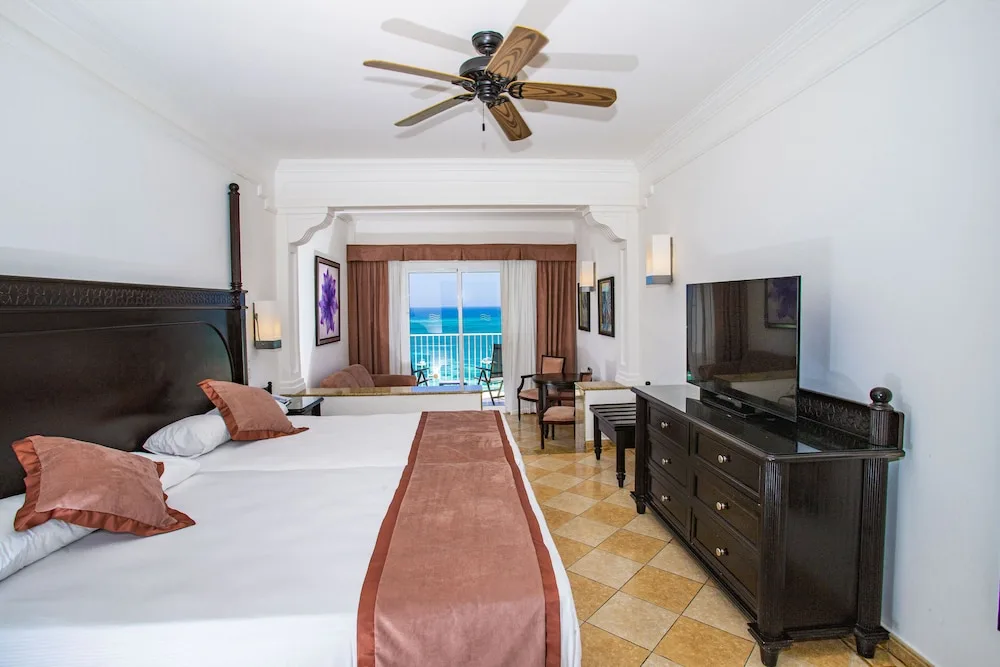 Junior Suite Ocean View with king bed, TV, and balcony at Hotel Riu Palace Aruba.