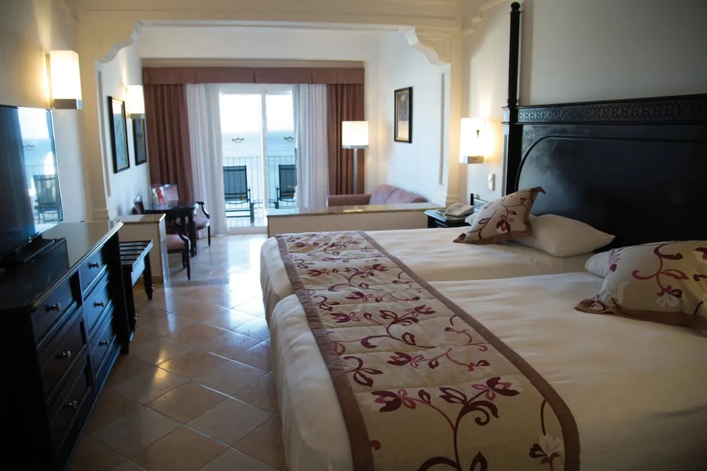 Junior Suite Ocean View with twin beds and balcony at Hotel Riu Palace Aruba.