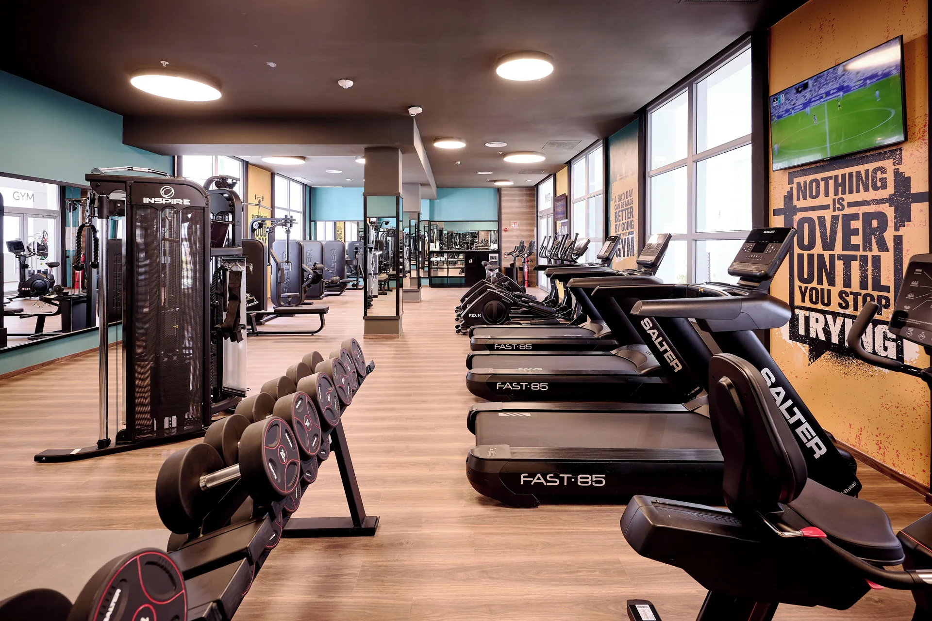 Gym with treadmills, weights, and wall-mounted TV at Hotel Riu Palace Bavaro.