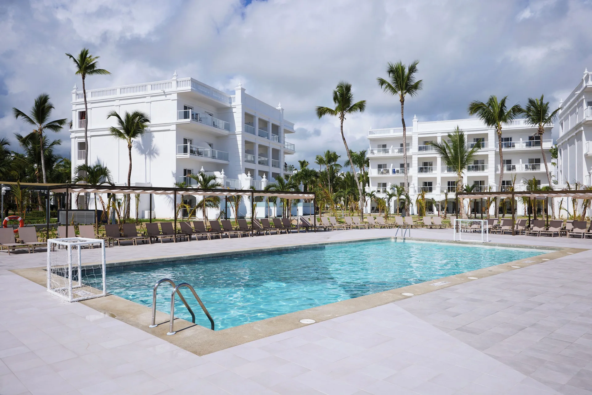 Pool courtyard with white guest buildings and palm trees at Hotel Riu Palace Bavaro.