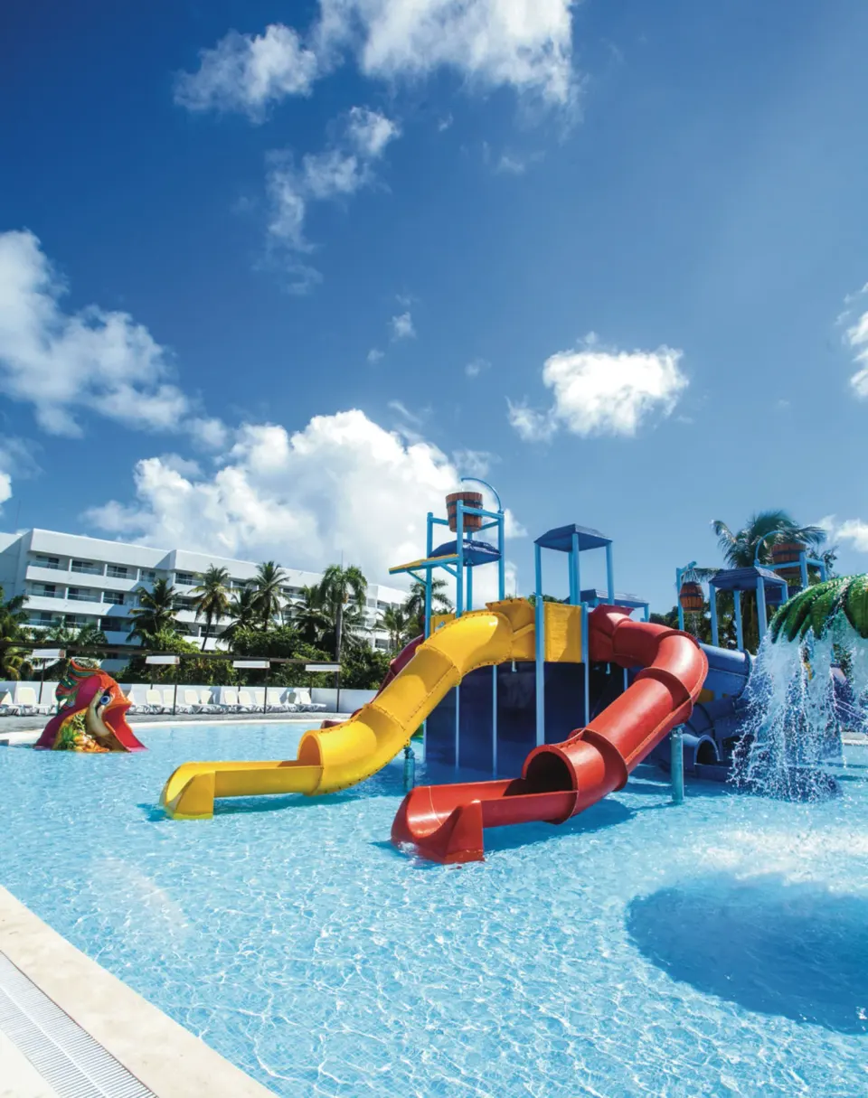 Shallow splash pool with yellow and red slides at Hotel Riu Palace Bavaro.
