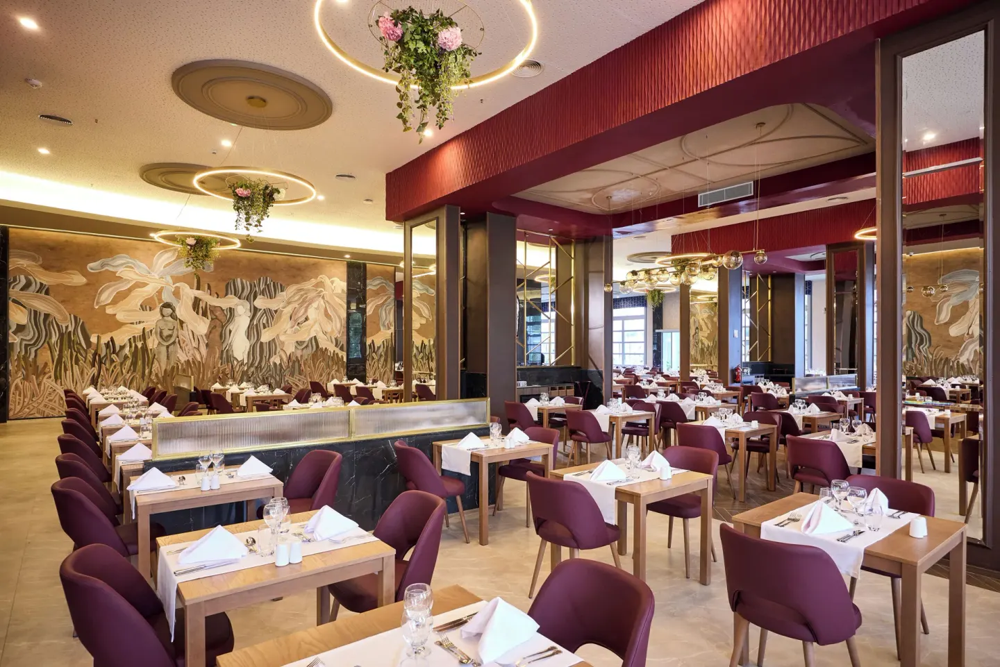 Large restaurant dining room with burgundy chairs and mural wall at Hotel Riu Palace Bavaro.