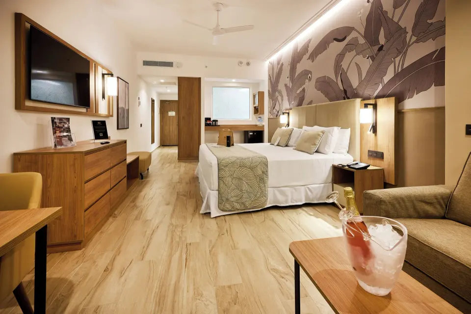 Elite Club swim-up junior suite with king bed, sofa, and TV at Hotel Riu Palace Bavaro.