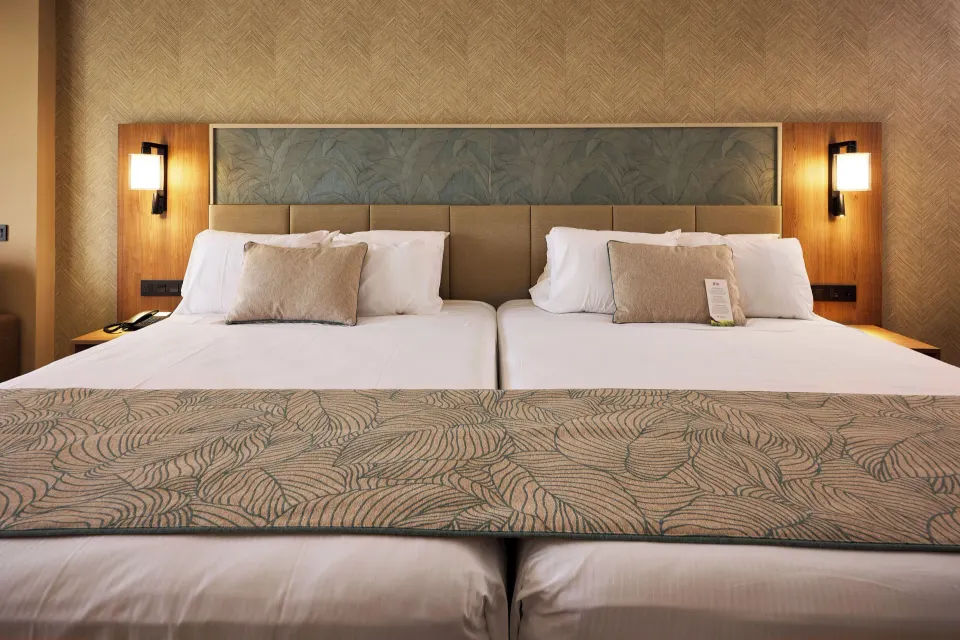 Close view of twin beds and padded headboard in Junior Suite Connecting Rooms at Hotel Riu Palace Bavaro.