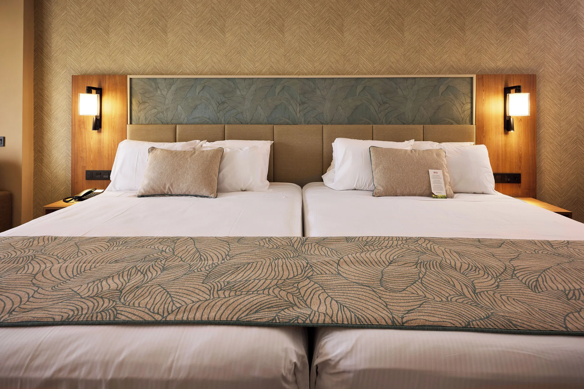 Close view of twin beds and padded headboard in Junior Suite Connecting Rooms at Hotel Riu Palace Bavaro.