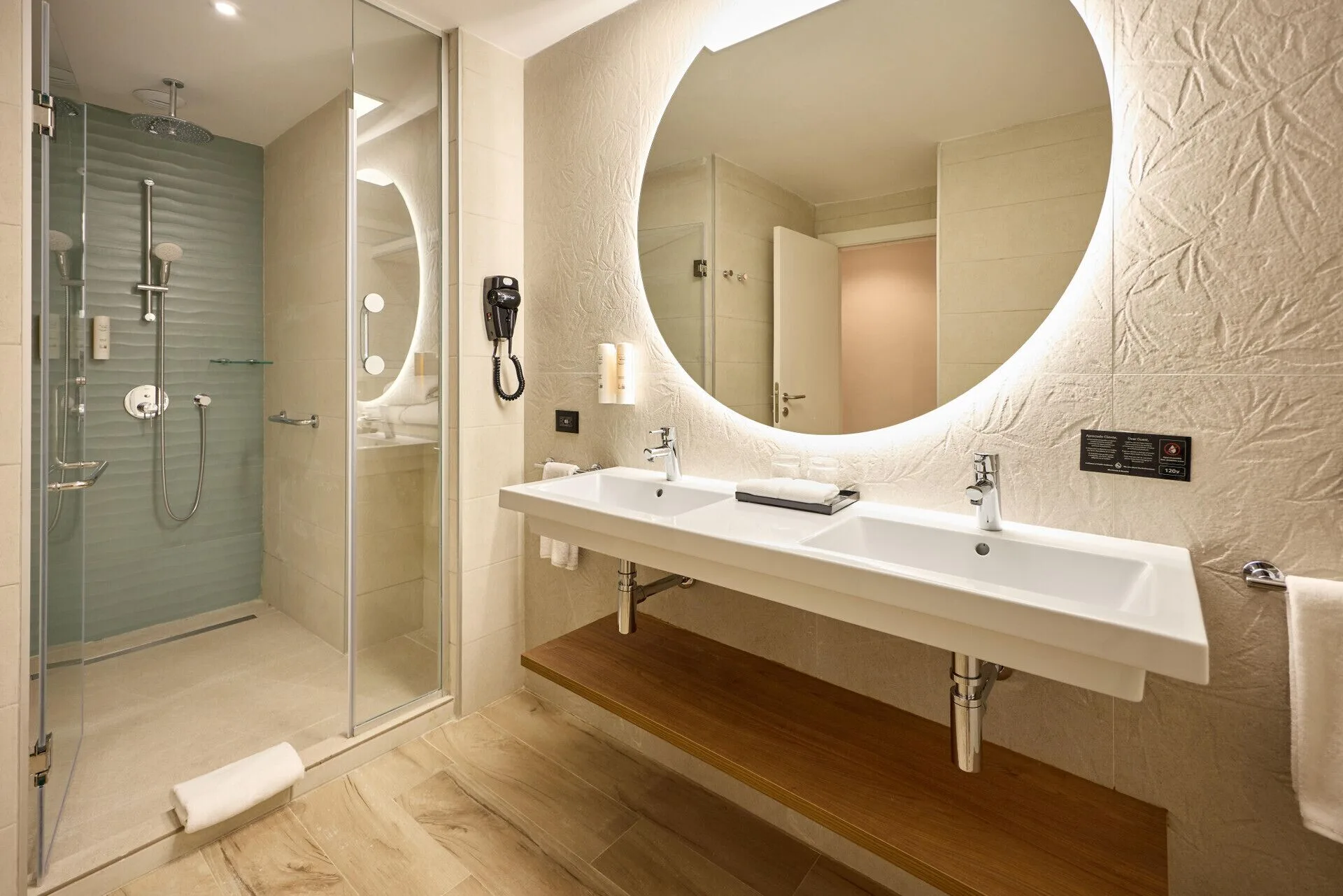 Junior Suite Garden View bathroom with lit mirror and glass shower at Hotel Riu Palace Bavaro.