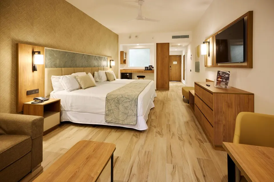 Junior Suite Garden View with two beds, dresser, and vanity at Hotel Riu Palace Bavaro.