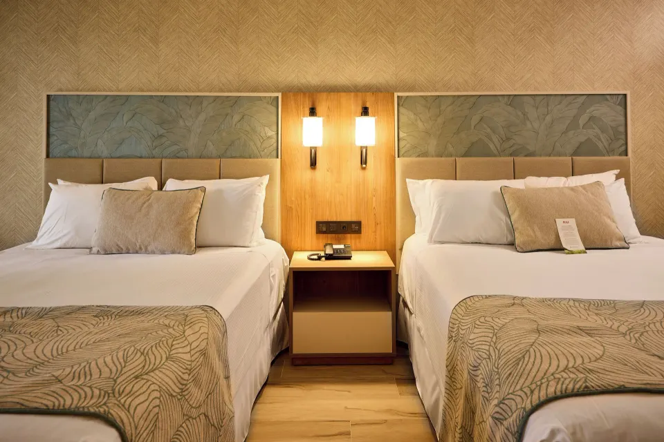 Two beds with shared nightstand in a Junior Suite at Hotel Riu Palace Bavaro.