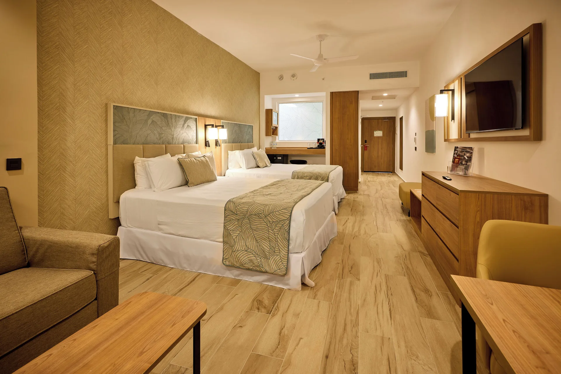 Junior Suite with two beds, sofa, desk, and TV at Hotel Riu Palace Bavaro.