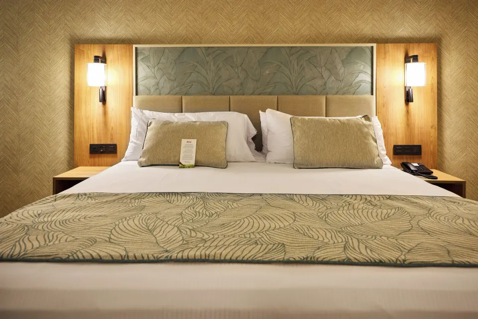 Junior Villa king bed close-up with lit sconces at Hotel Riu Palace Bavaro.
