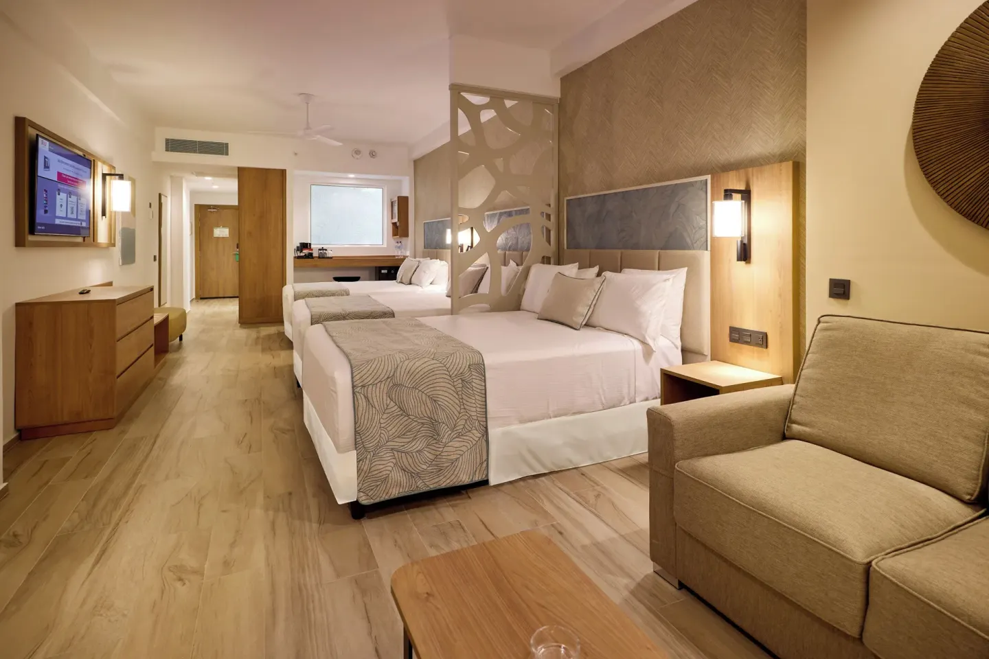 Friends and Family room with beds, sofa, TV and vanity at Hotel Riu Palace Bavaro.