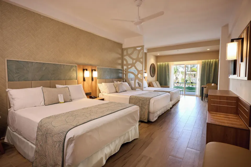 Friends and Family room with multiple beds and balcony at Hotel Riu Palace Bavaro.
