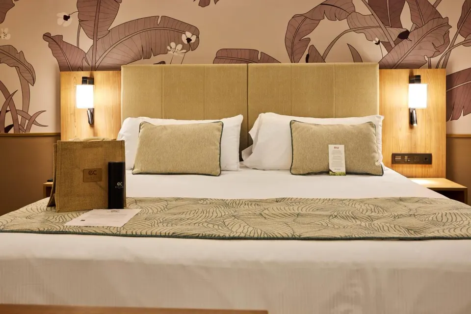 Suite king bed with leaf-pattern wall and bedside lights at Hotel Riu Palace Bavaro.