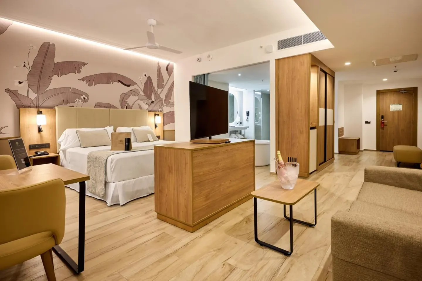 Ocean-view suite with king bed, sofa, TV, and desk at Hotel Riu Palace Bavaro.