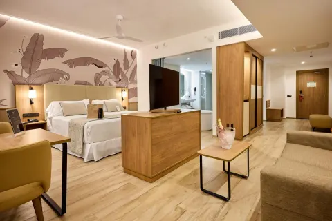 Ocean-view suite with king bed, sofa, TV, and desk at Hotel Riu Palace Bavaro.