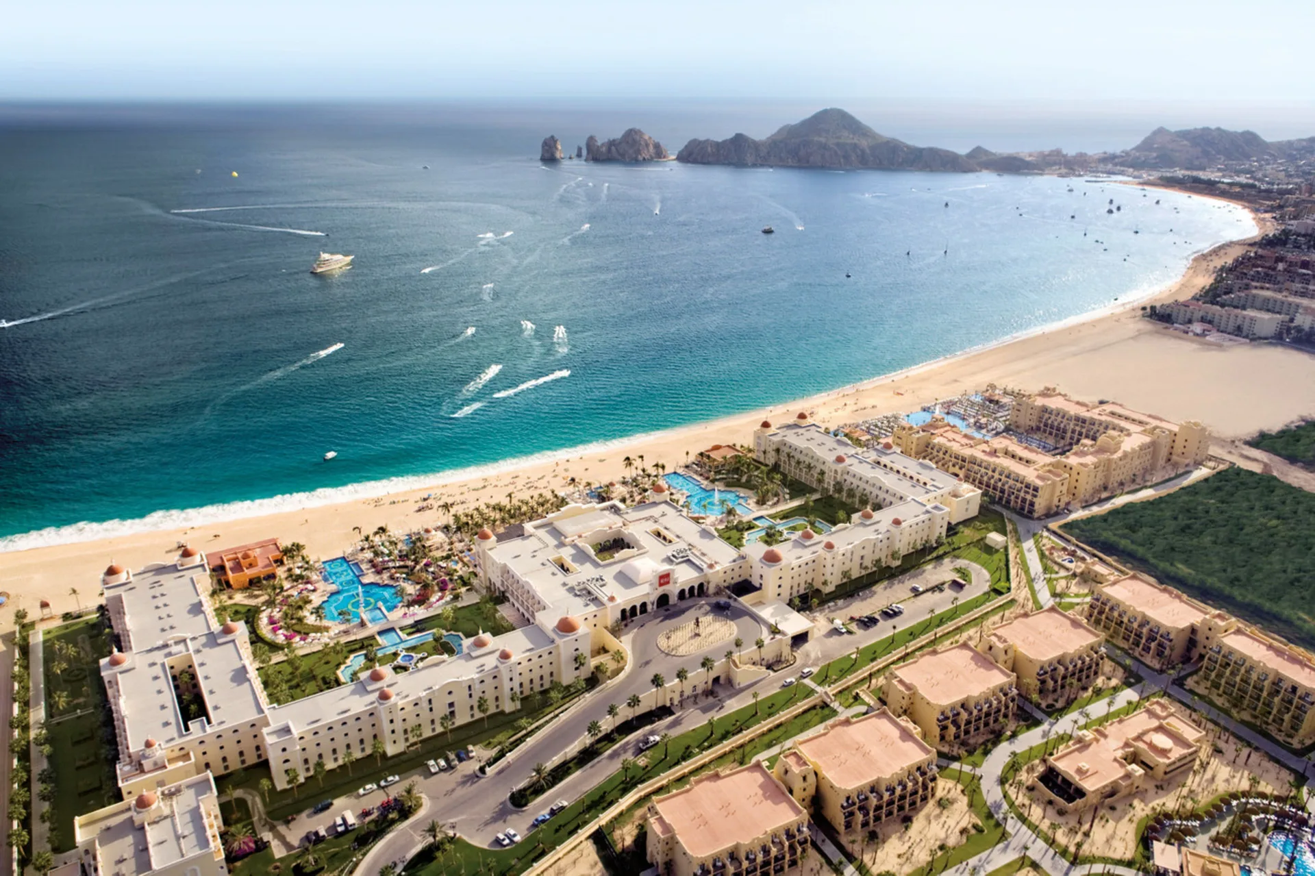 Aerial view of Hotel Riu Palace Cabo San Lucas on the beach with Land's End beyond.