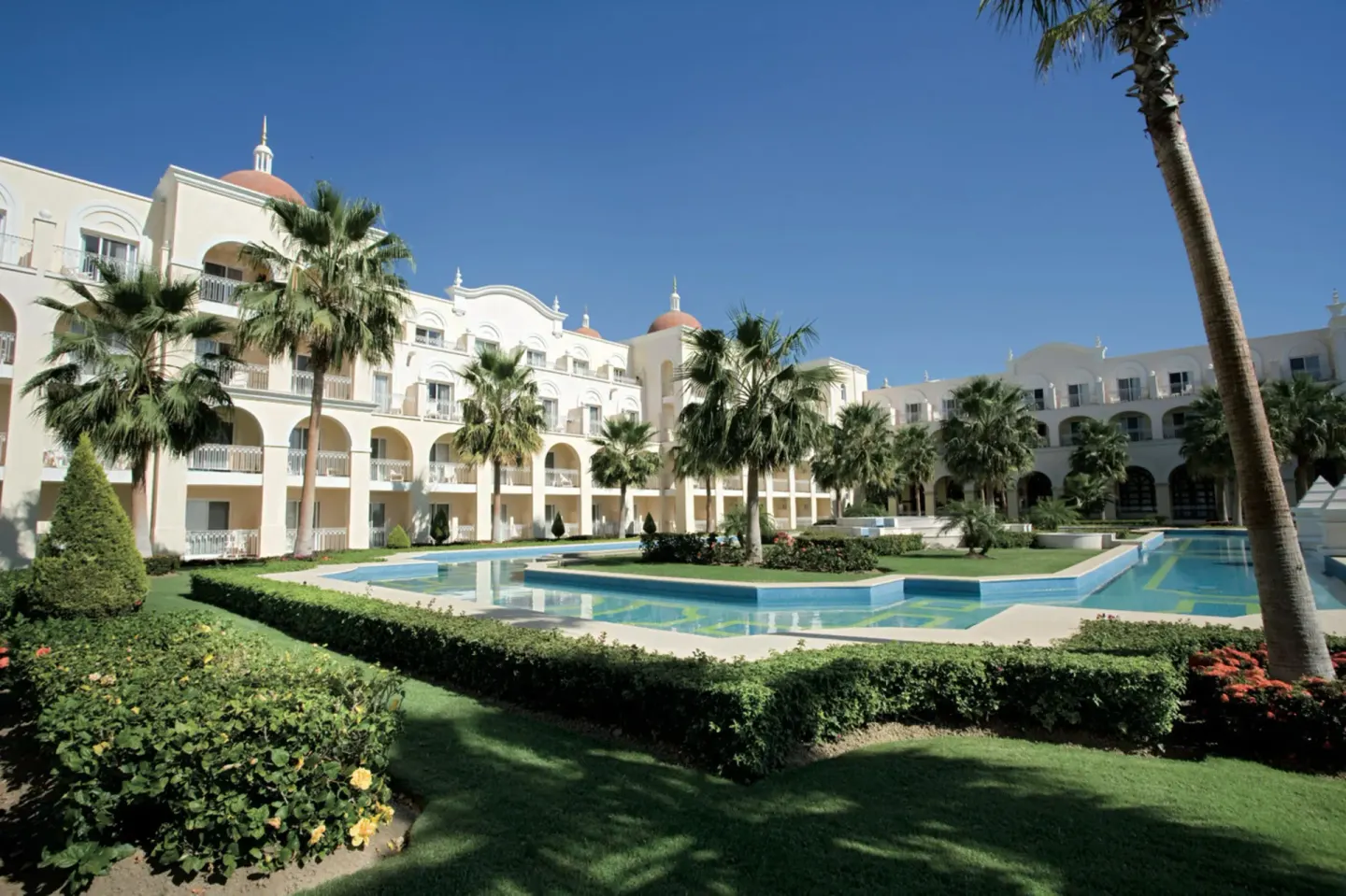 Courtyard pool and palm-lined gardens at Hotel Riu Palace Cabo San Lucas.