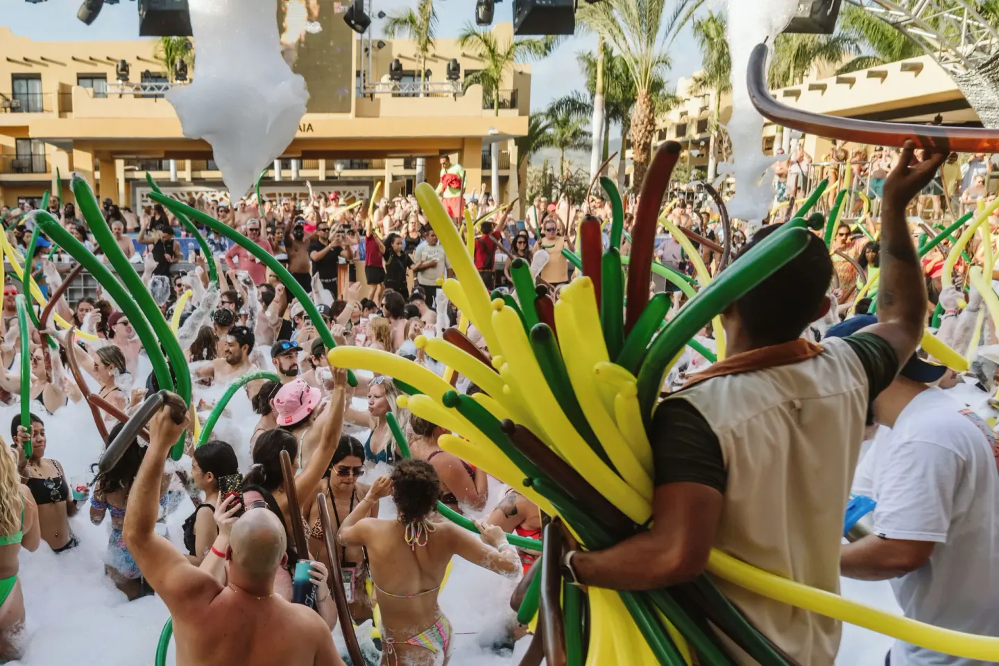 Crowded foam pool party with balloon tubes at Hotel Riu Palace Cabo San Lucas.