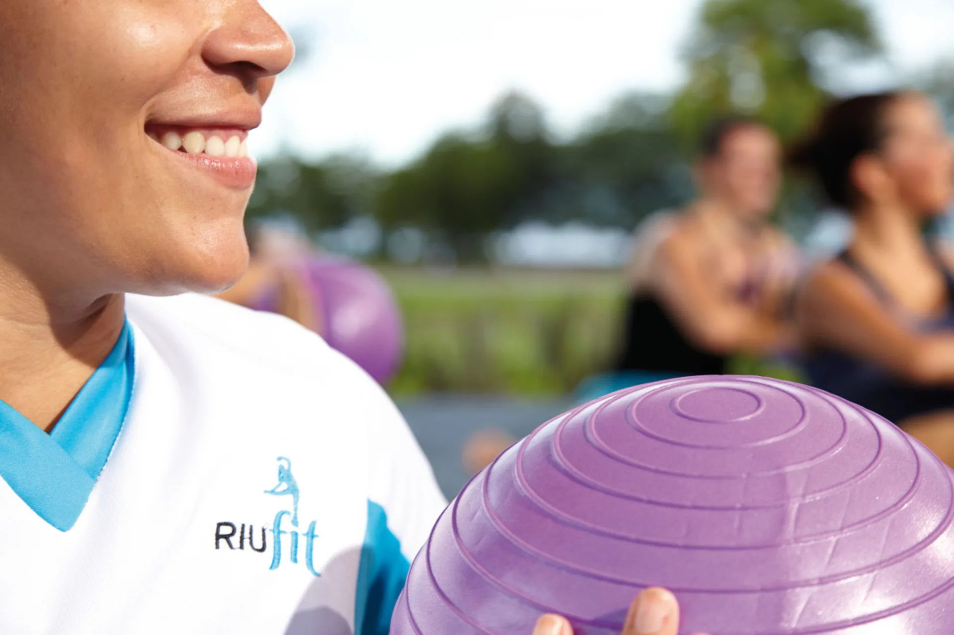 Fitness instructor holding an exercise ball at Hotel Riu Palace Cabo San Lucas.