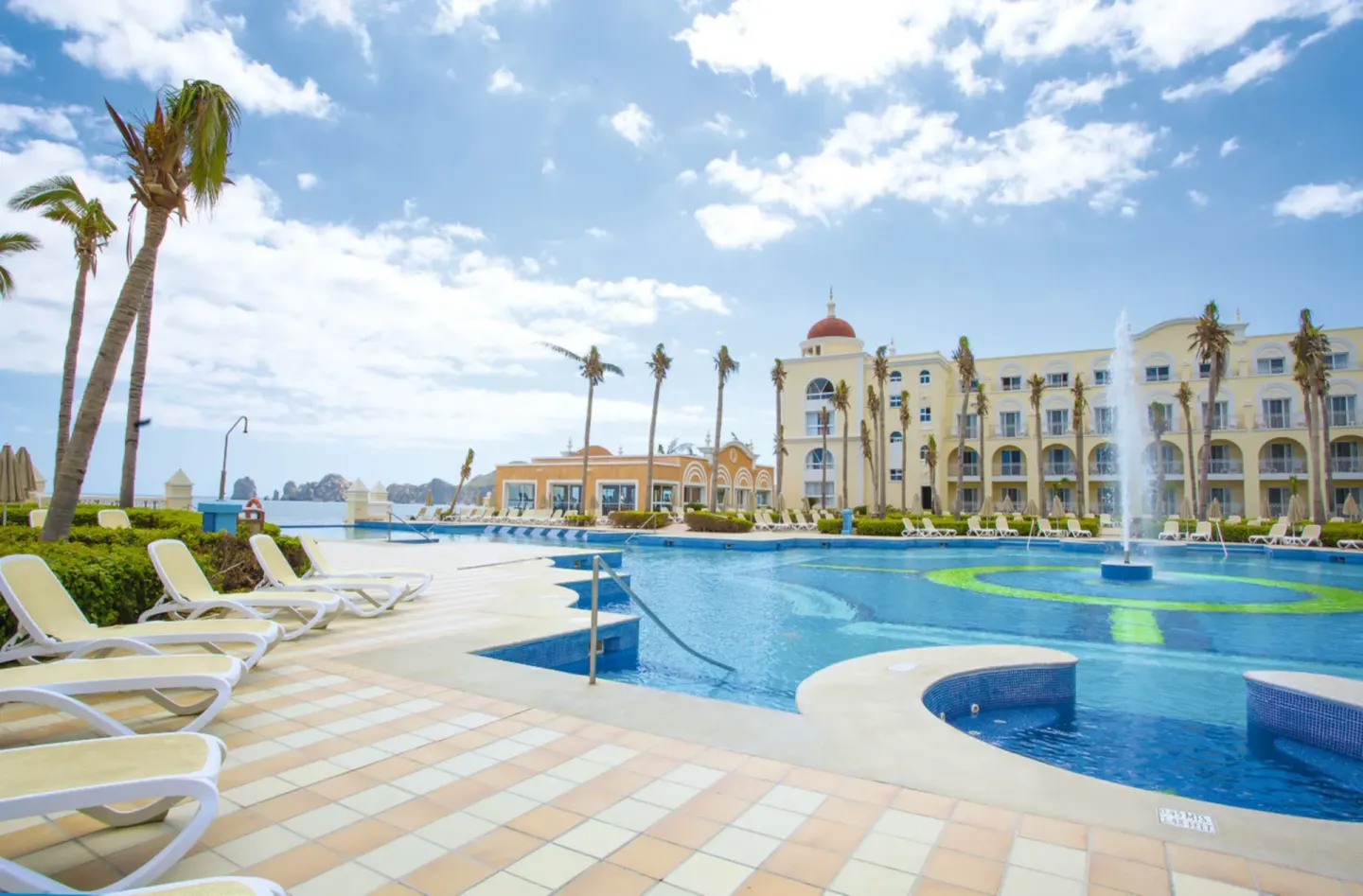 Pool deck, fountain, loungers, and resort buildings at Hotel Riu Palace Cabo San Lucas.