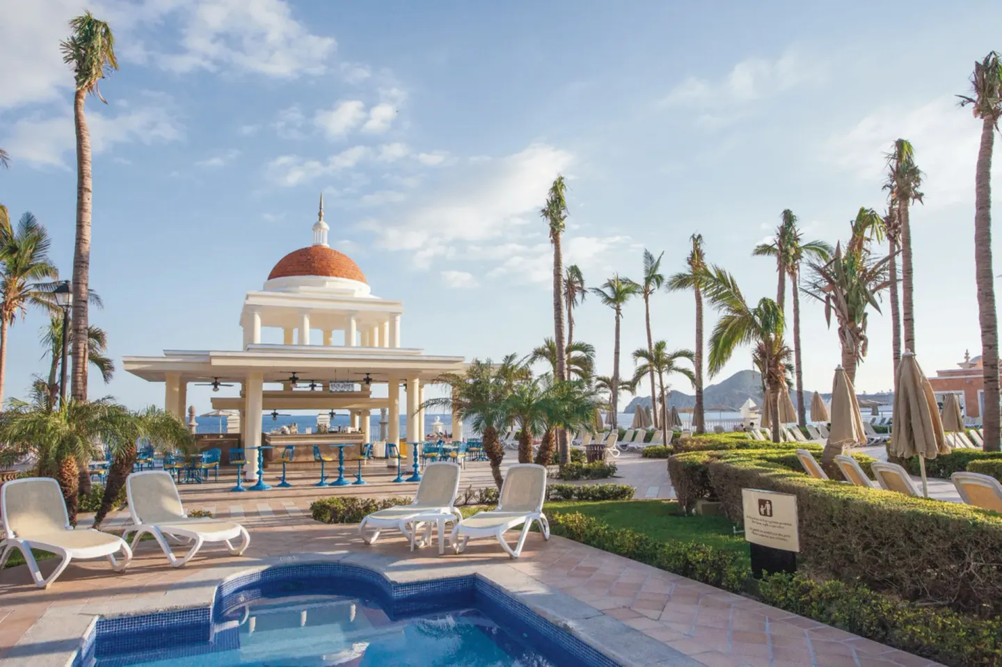 Poolside lounge chairs and a domed pavilion at Hotel Riu Palace Cabo San Lucas.