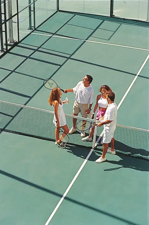 Guests with rackets on a tennis court at Hotel Riu Palace Cabo San Lucas.