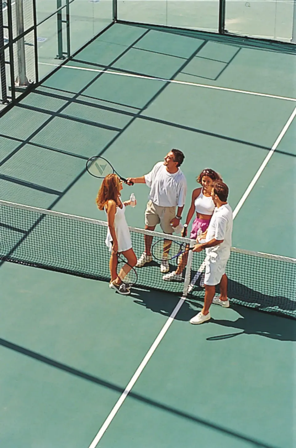Guests with rackets on a tennis court at Hotel Riu Palace Cabo San Lucas.