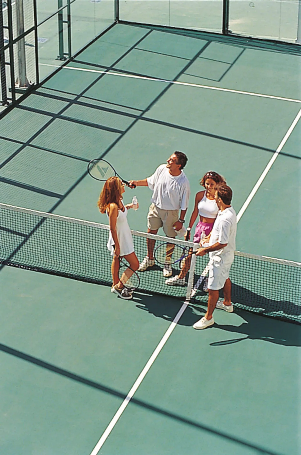 Guests with rackets on a tennis court at Hotel Riu Palace Cabo San Lucas.