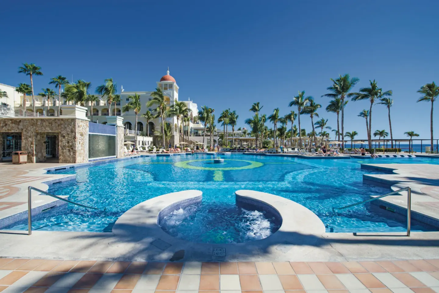 Wide resort pool with a round spa feature at Hotel Riu Palace Cabo San Lucas.
