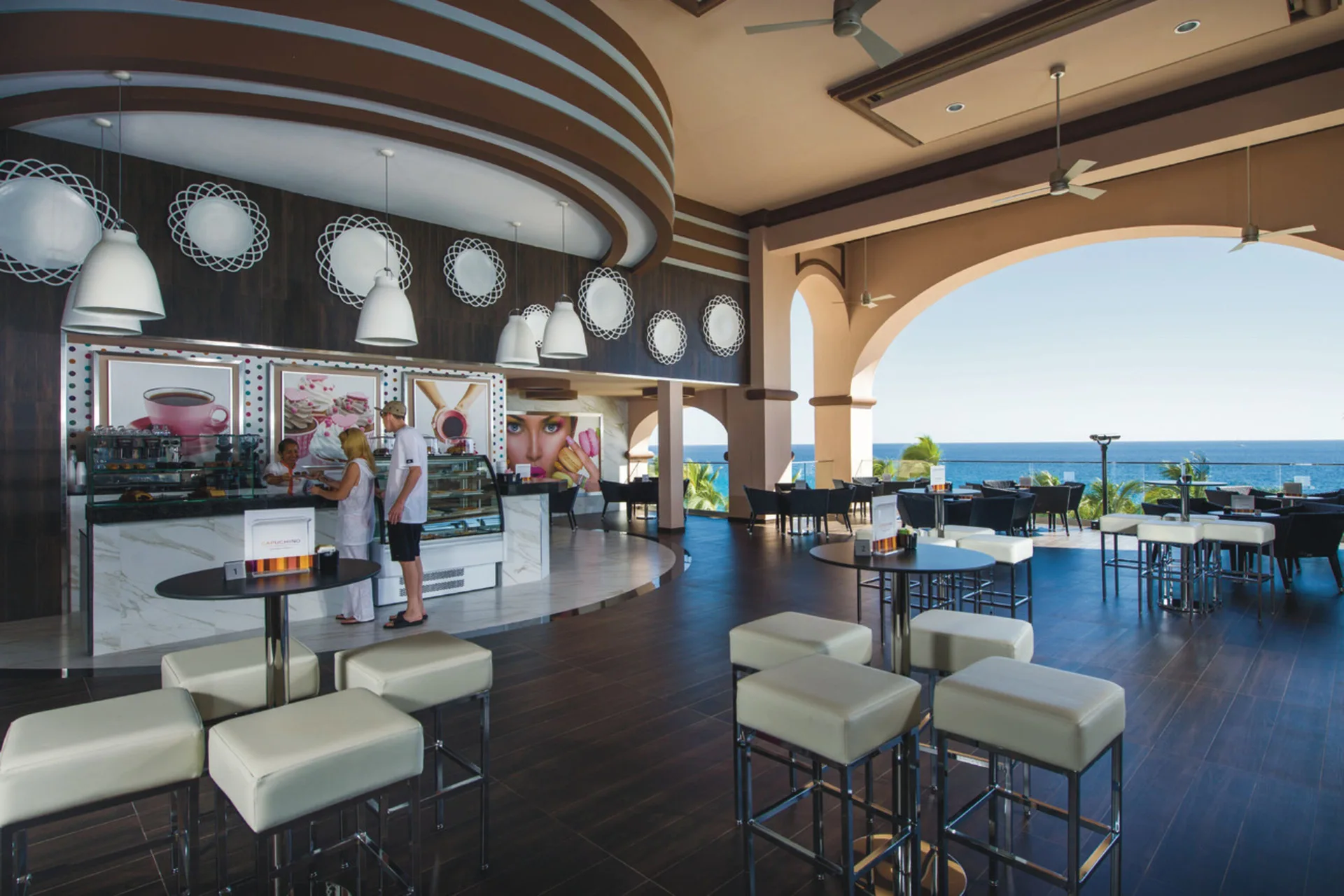 Open-air café seating with pastry cases and ocean view at Hotel Riu Palace Cabo San Lucas.