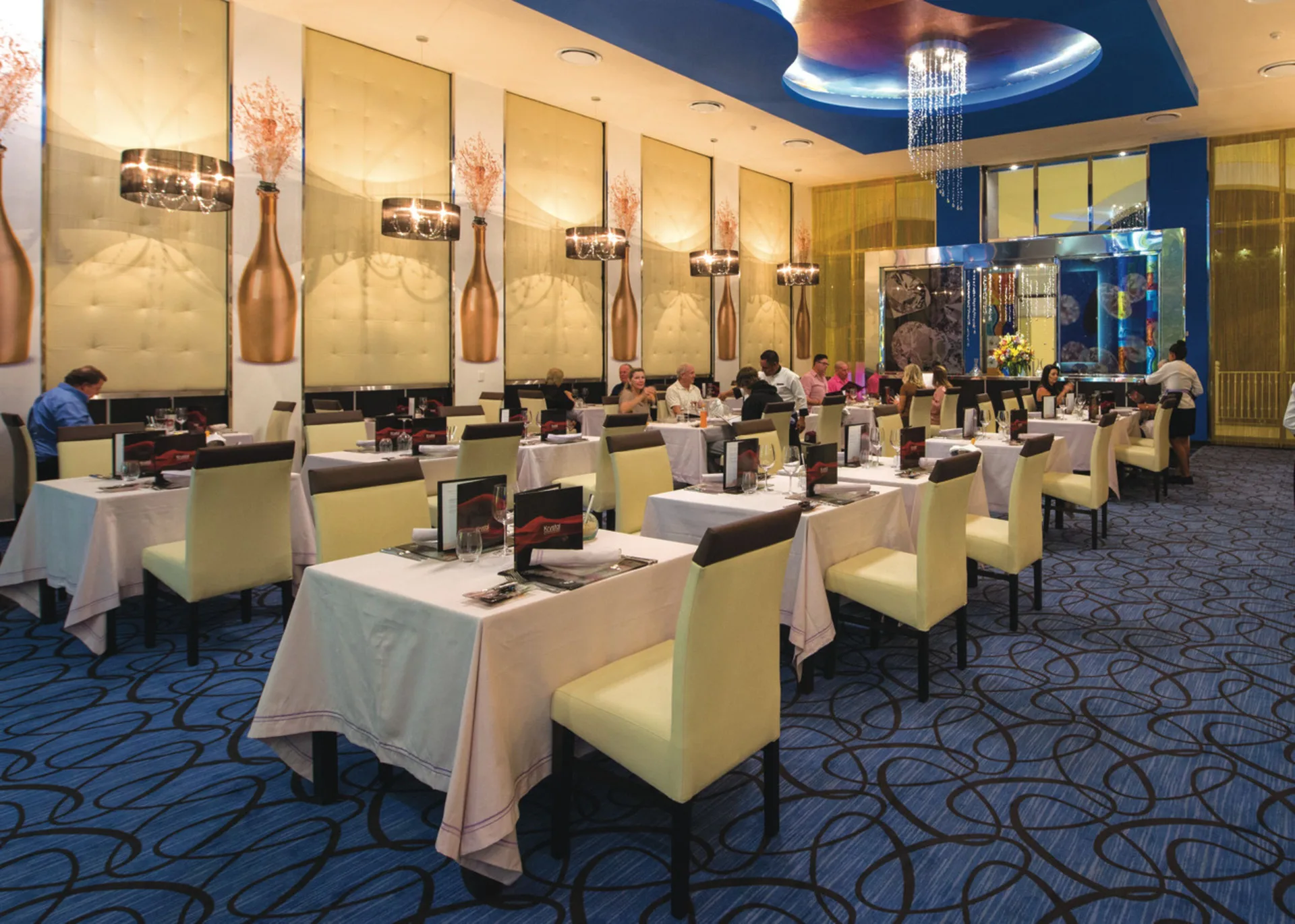 Elegant dining room with set tables and blue carpet at Hotel Riu Palace Cabo San Lucas.