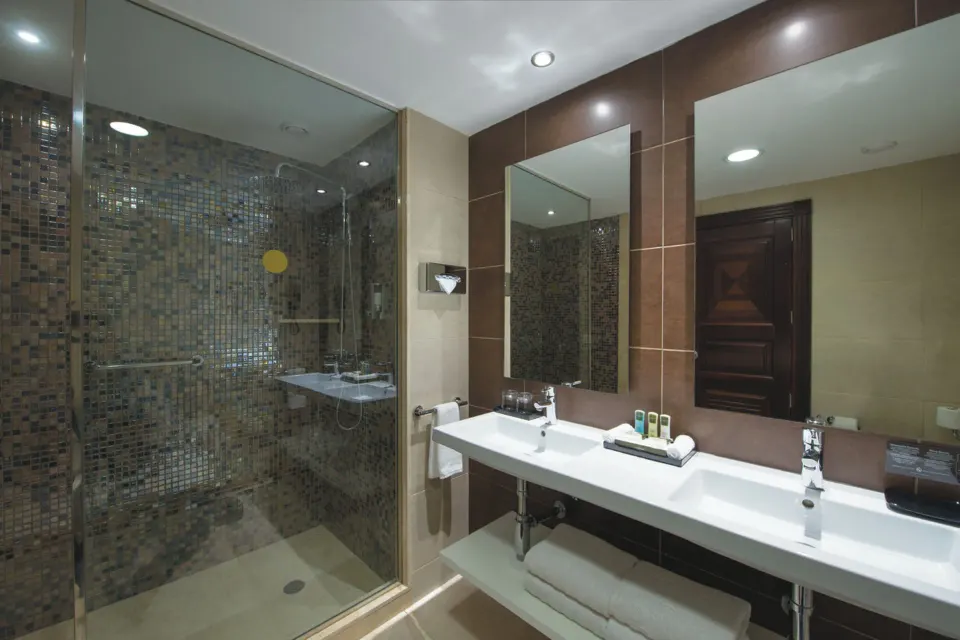 Ocean View room bathroom with double sinks and glass shower at Hotel Riu Palace Cabo San Lucas.