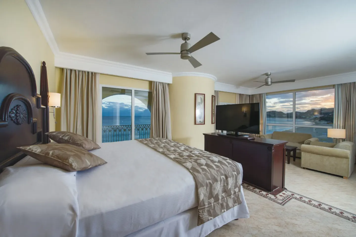Ocean-view suite bedroom with king bed and sitting area at Hotel Riu Palace Cabo San Lucas.
