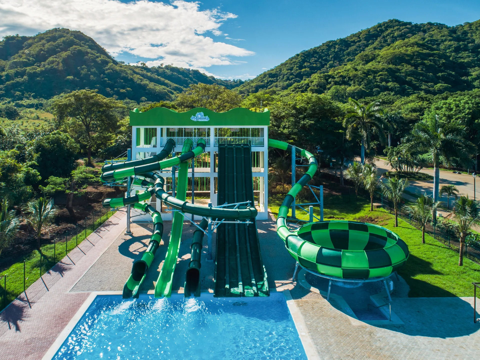 Large green waterslides with mountain backdrop at Hotel Riu Palace Costa Rica.
