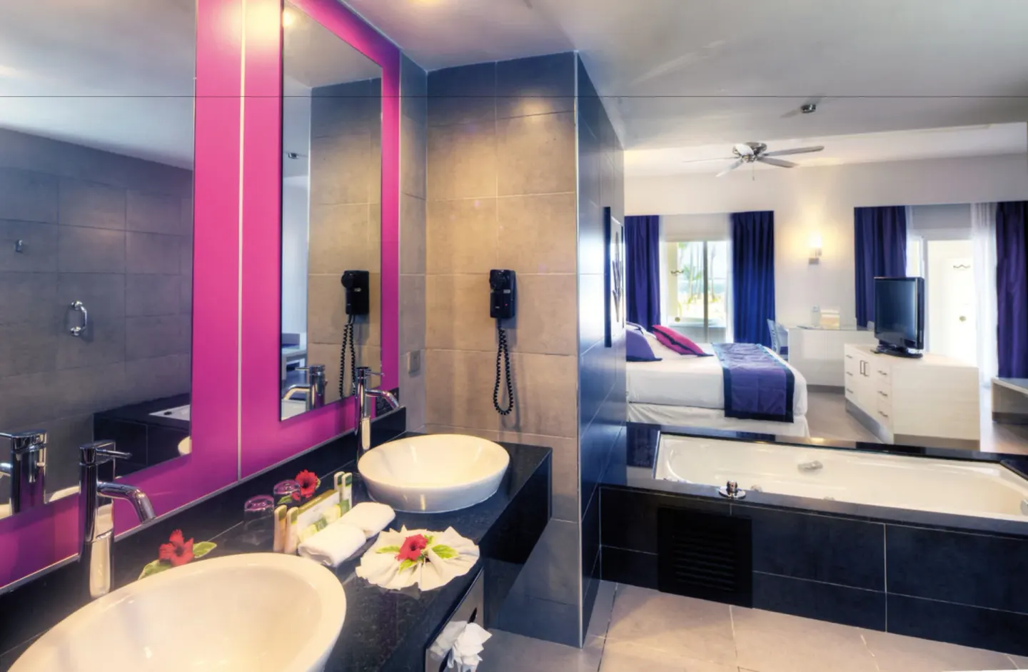 Guest room vanity with double sinks and tub beside the bedroom at Hotel Riu Palace Costa Rica.