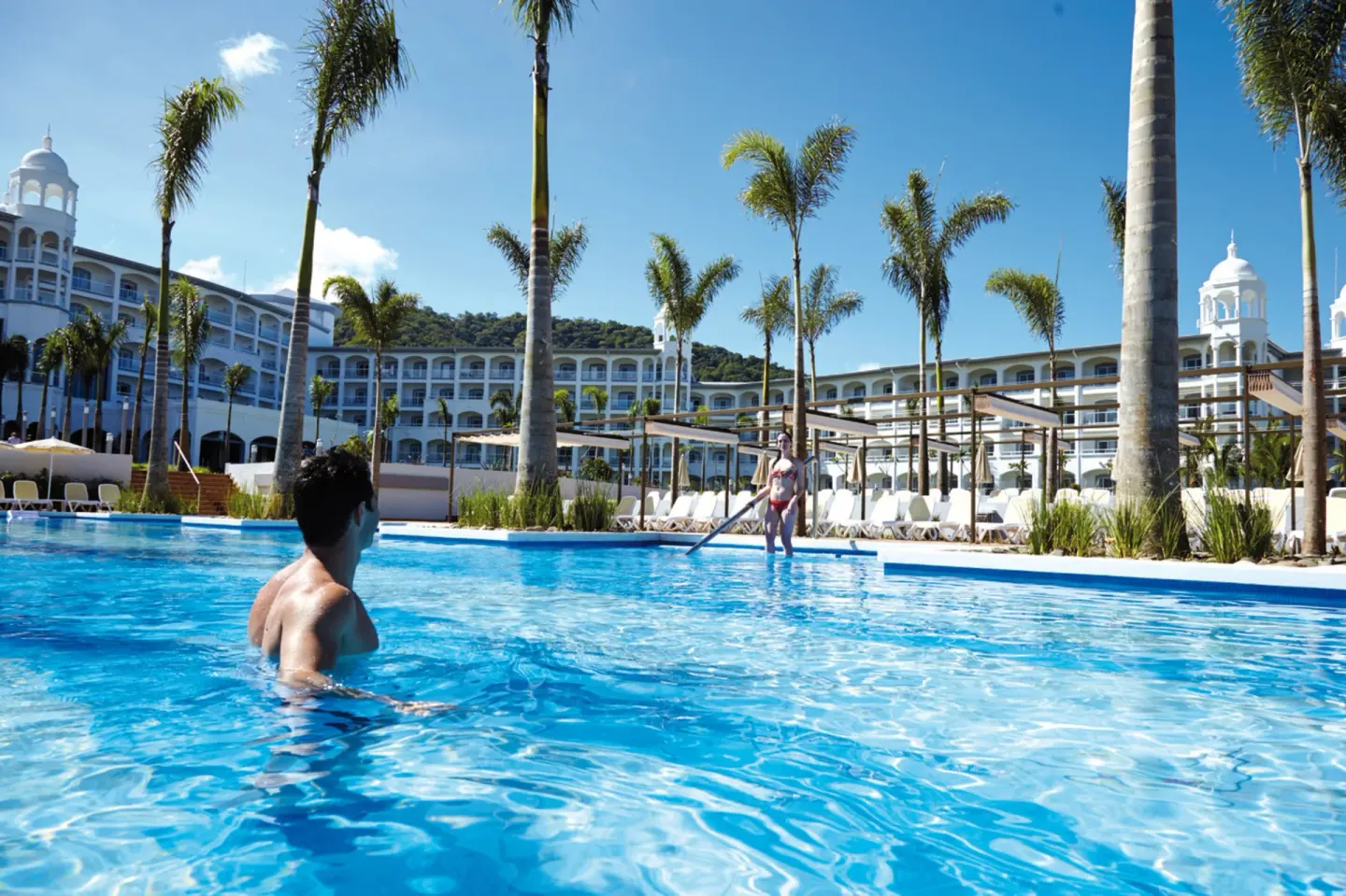 Guests in a large palm-lined pool at Hotel Riu Palace Costa Rica.