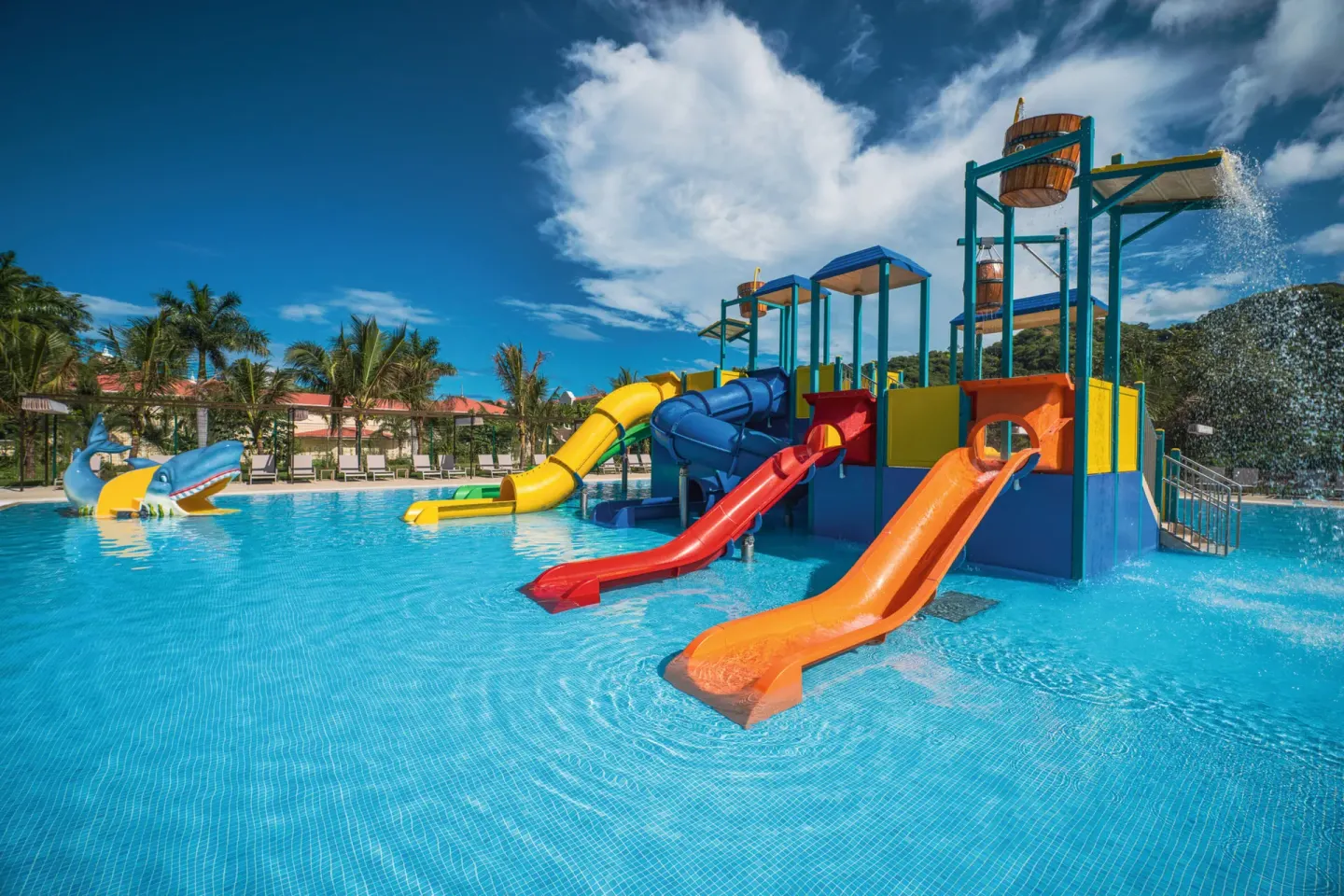 Splash pool with bucket water features and bright slides at Hotel Riu Palace Costa Rica.