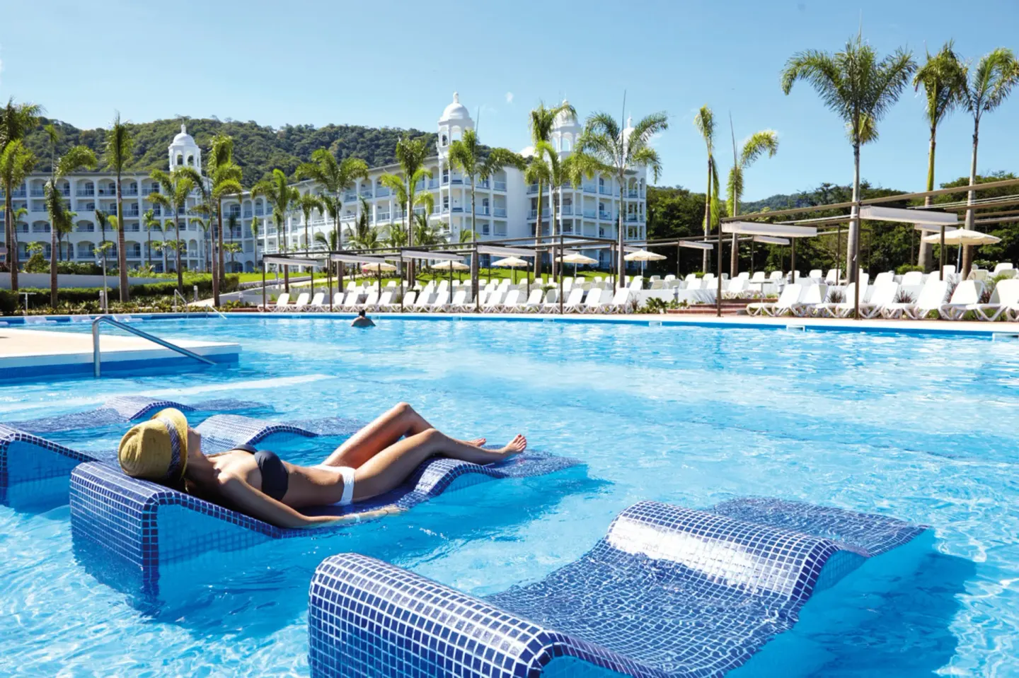 Guest sunbathing on an in-water pool lounger at Hotel Riu Palace Costa Rica.