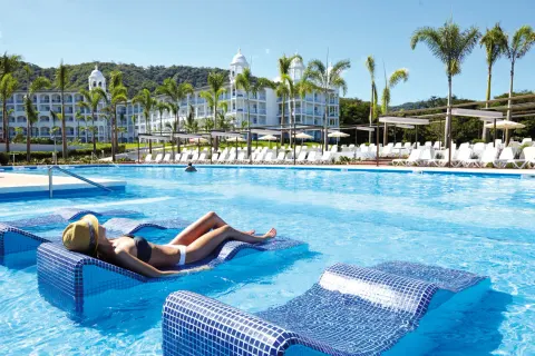 Guest sunbathing on an in-water pool lounger at Hotel Riu Palace Costa Rica.