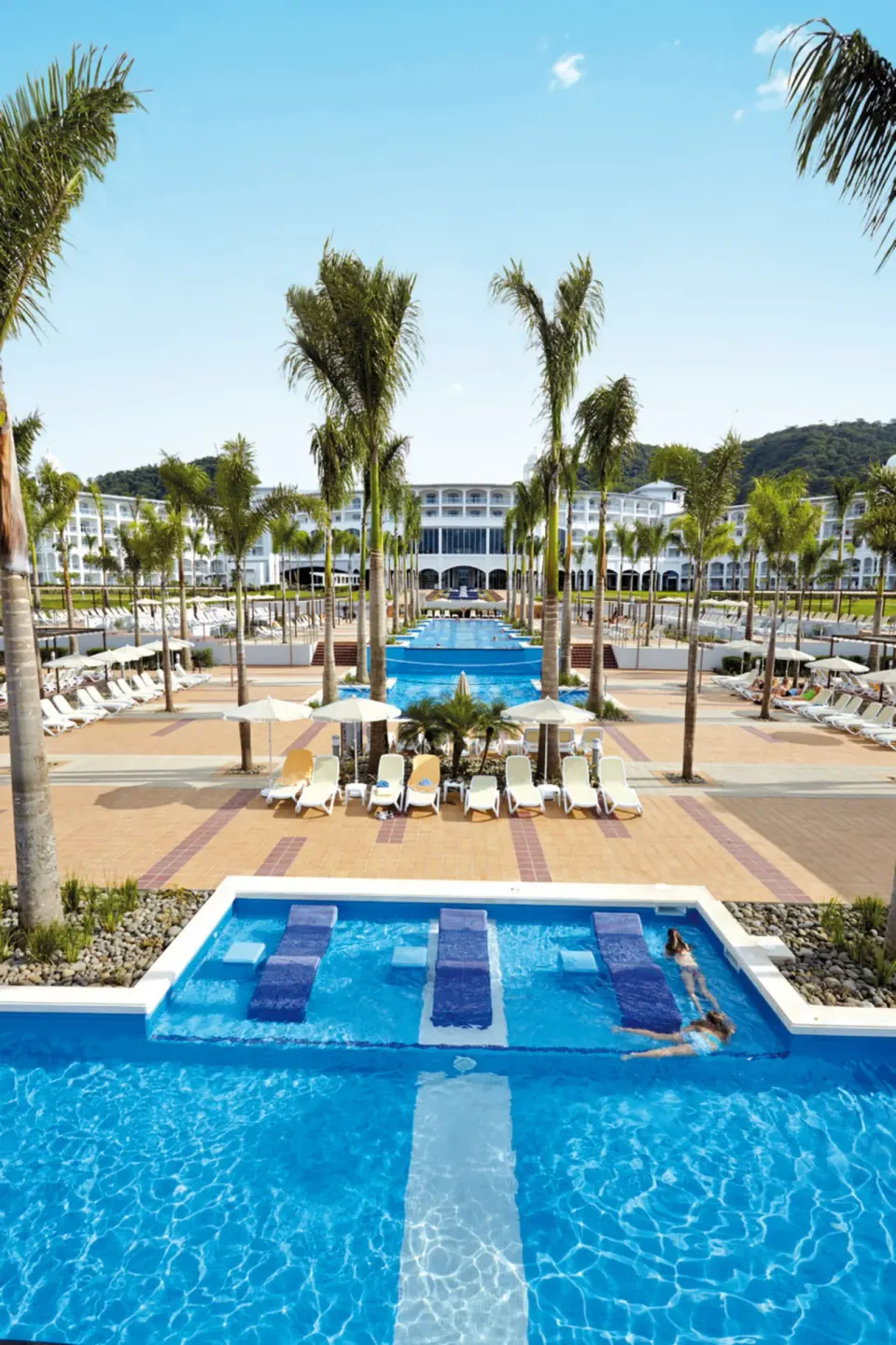 Long view over tiered pools and palm decks at Hotel Riu Palace Costa Rica.