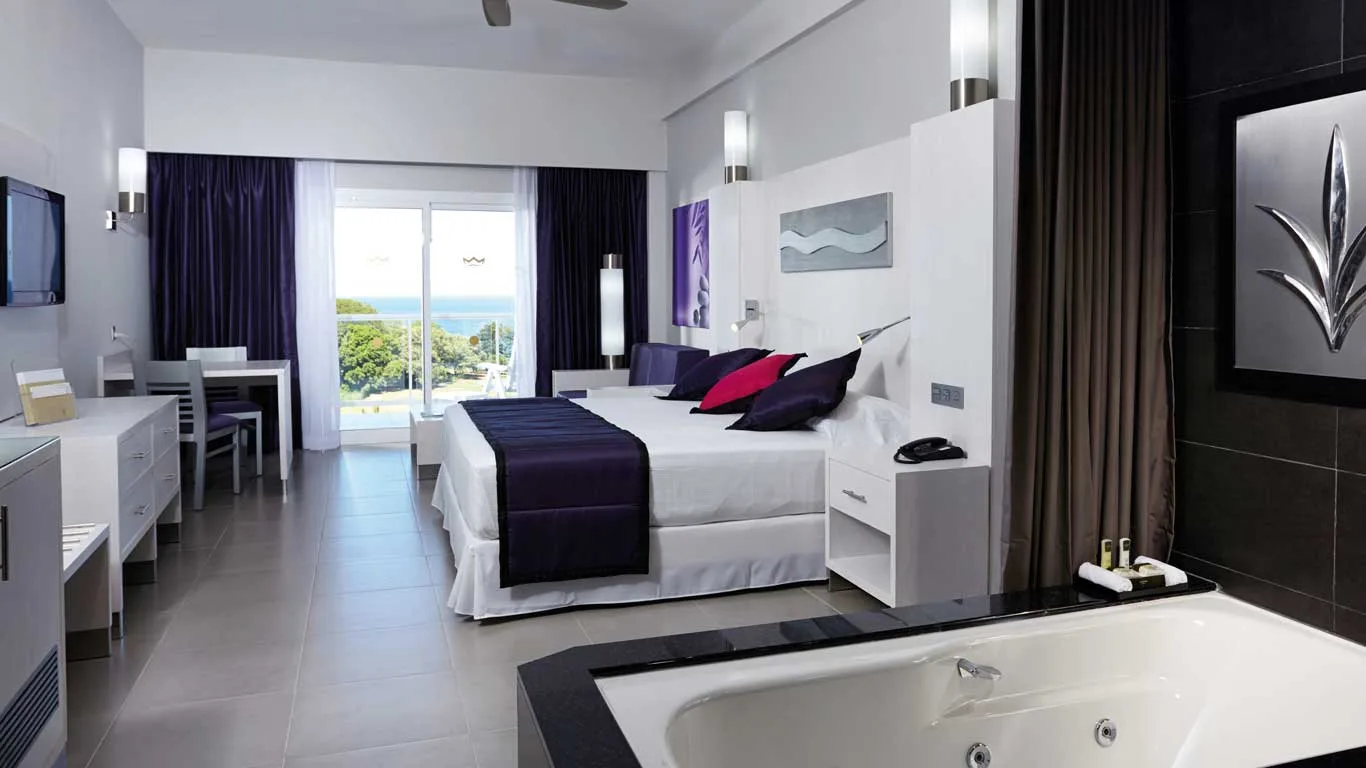 King bed beside the in-room whirlpool tub with a sea-view balcony in the Sea View Whirlpool Suite at Hotel Riu Palace Costa Rica.