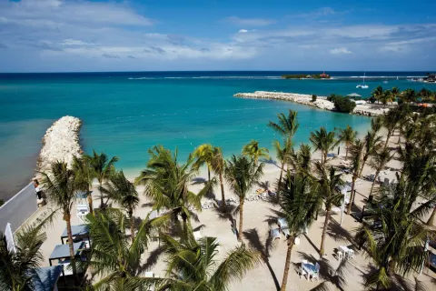 Aerial view of the beach, palm trees, and turquoise bay at Hotel Riu Palace Jamaica.