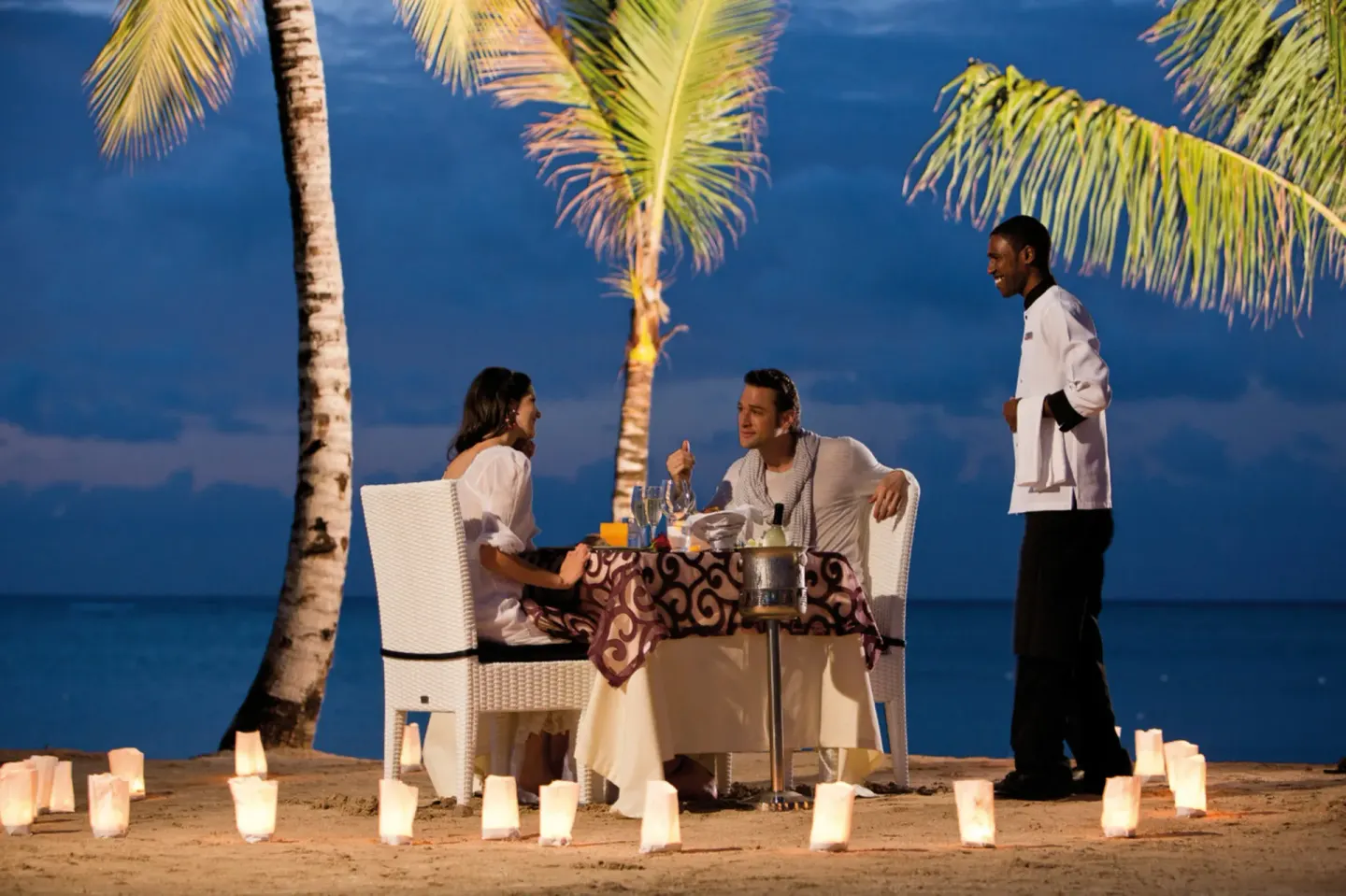 A couple dines by candlelight on the beach at Hotel Riu Palace Jamaica.
