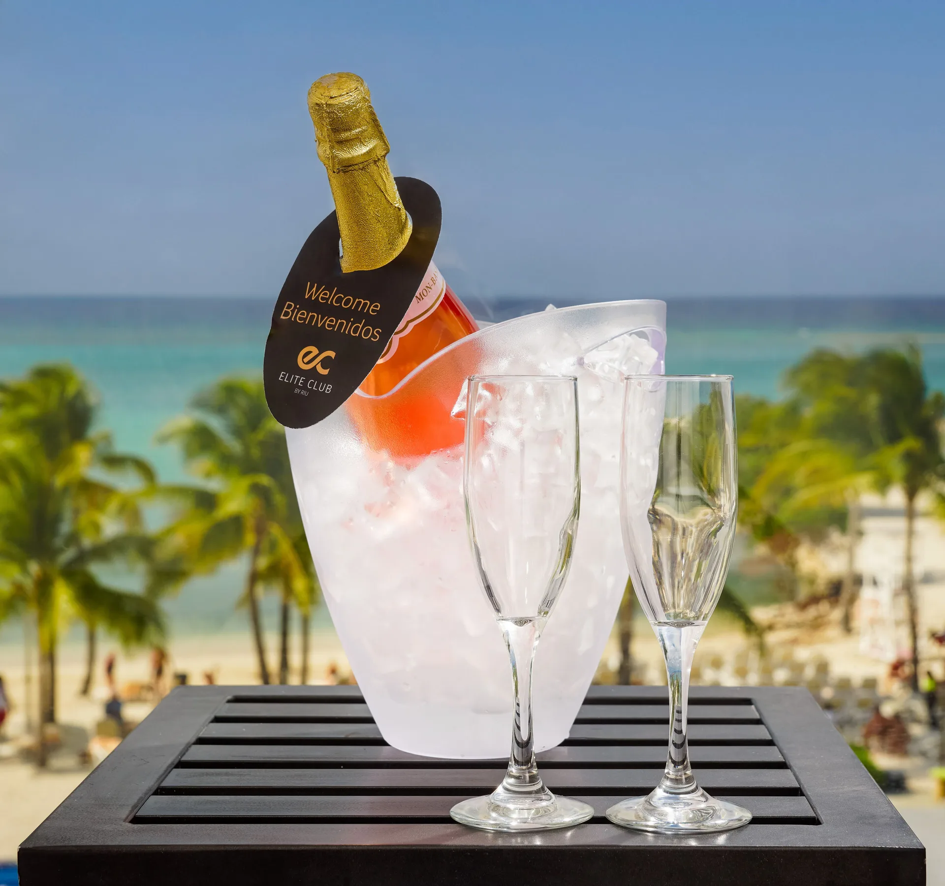 A chilled bottle and two flutes are set before a beach view at Hotel Riu Palace Jamaica.