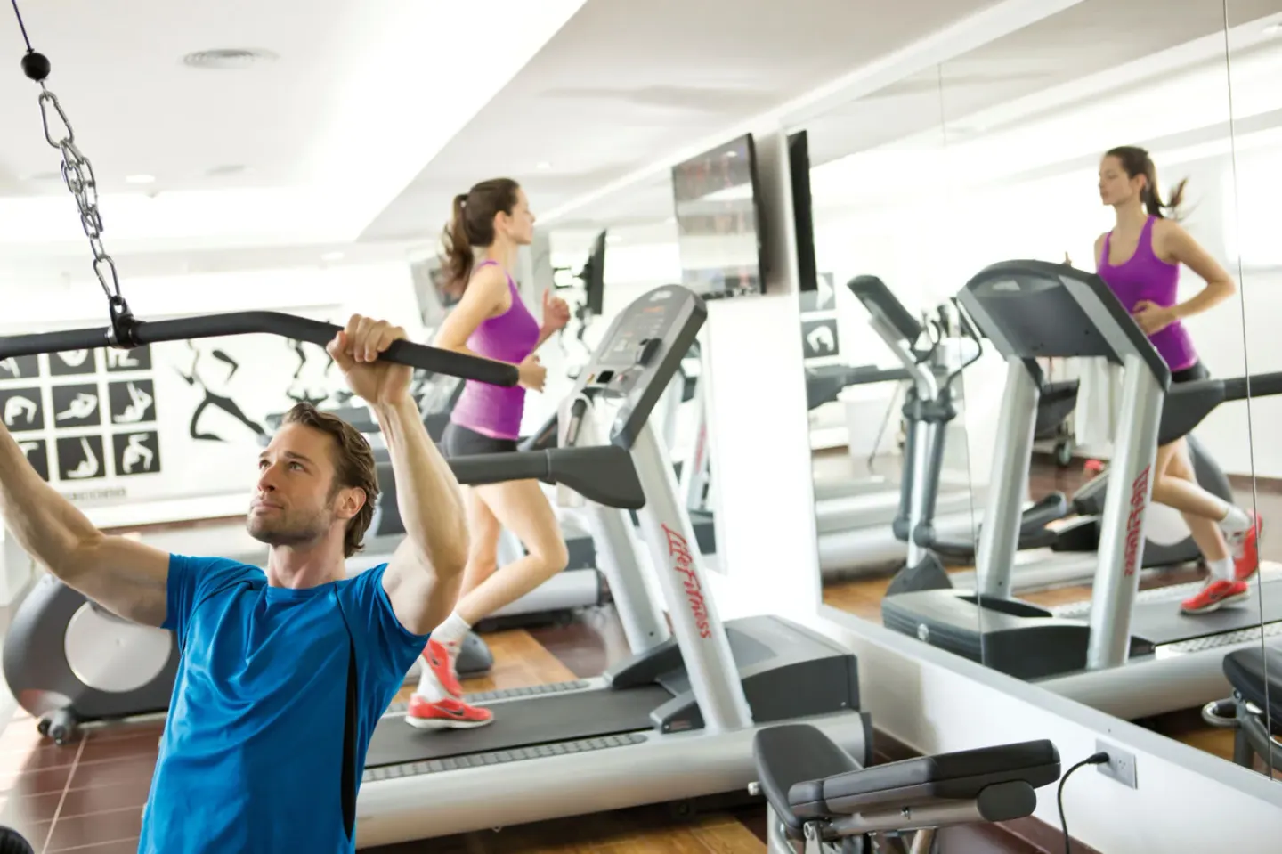 Guests use treadmills and strength equipment in the fitness room at Hotel Riu Palace Jamaica.